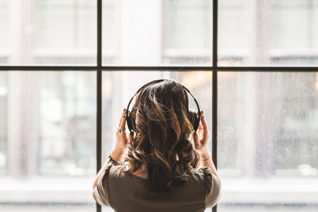 Frau steht am Fenster und hört Podcast-Trends auf podcast.de